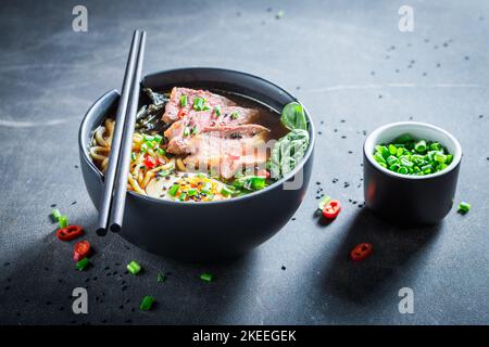 Deliziosa e aromatica zuppa Ramen servita con erba cipollina e sesamo. Zuppa Ramen classica con carne e alghe. Foto Stock