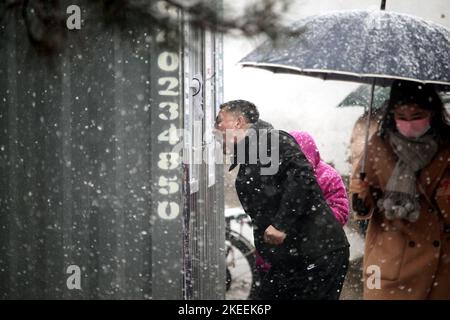 SHENYANG, CINA - NOVEMBER12, 2022 - la gente tiene gli ombrelli sotto la neve per il test degli acidi nucleici a Shenyang, provincia di Liaoning, Cina, 12 novembre 2022. Foto Stock