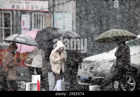 SHENYANG, CINA - NOVEMBER12, 2022 - la gente aspetta in fila sotto gli ombrelli nella neve per il test degli acidi nucleici a Shenyang, provincia di Liaoning, Cina, N. Foto Stock