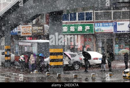 SHENYANG, CINA - NOVEMBER12, 2022 - la gente aspetta in fila sotto gli ombrelli nella neve per il test degli acidi nucleici a Shenyang, provincia di Liaoning, Cina, N. Foto Stock