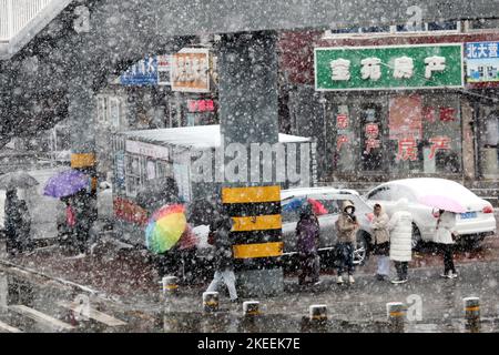 SHENYANG, CINA - NOVEMBER12, 2022 - la gente aspetta in fila sotto gli ombrelli nella neve per il test degli acidi nucleici a Shenyang, provincia di Liaoning, Cina, N. Foto Stock