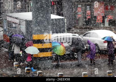 SHENYANG, CINA - NOVEMBER12, 2022 - la gente aspetta in fila sotto gli ombrelli nella neve per il test degli acidi nucleici a Shenyang, provincia di Liaoning, Cina, N. Foto Stock