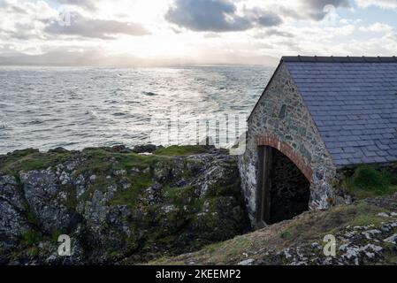 Vecchia stazione di scialuppa sotto il faro di Twr Bach sull'isola di Llanddwyn, Anglesey, Galles del Nord. Foto Stock