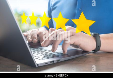 primo piano uomo del cliente mano a digitare sulla tastiera del notebook per dare un 5 stelle per il servizio di revisione. 5star concetto di testimonianza e revisione, la gente usa il computer Foto Stock