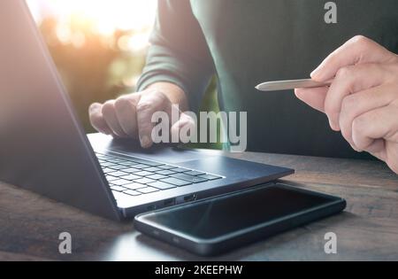 mani di primo piano di un uomo d'affari che lavora su un computer portatile e usando una penna che fa avvisi. lavoro sul computer. Dispositivo tecnologico, contattare l'azienda di comunicazione pe Foto Stock