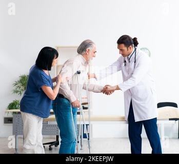 La vecchia coppia visitando giovane maschio medico Foto Stock