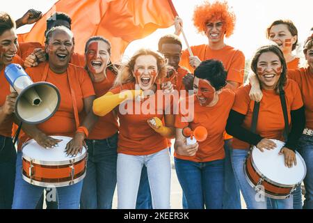 Tifosi di sport multirazziali che urlano mentre sostengono la loro squadra - tifosi di calcio che si divertono all'evento di competizione - Focus on center girl face Foto Stock