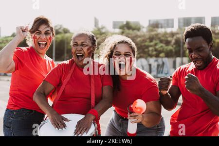 Gli appassionati di calcio si divertono a allietare la loro squadra preferita: Il concetto di sport di calcio per l'intrattenimento Foto Stock