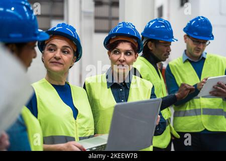 Team di ingegneri diversi che lavorano in fabbrica robotica - concetto industriale Tech Foto Stock