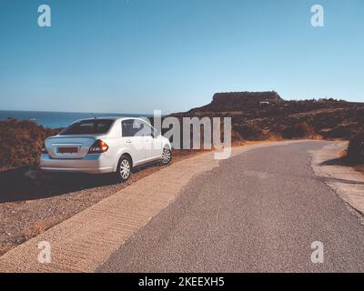 Auto bianca sulla strada del deserto di montagna. Autunno paesaggio naturale. Concetto di viaggio, turismo, vacanza, libertà e stile di vita attivo. Cipro Foto Stock