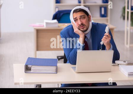 Giovane impiegato di uomini d'affari che soffre di mal di denti sul posto di lavoro Foto Stock