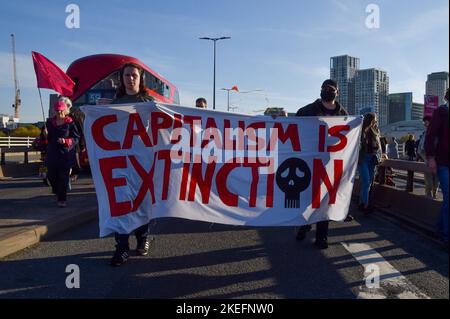 Londra, Inghilterra, Regno Unito. 12th Nov 2022. I manifestanti di Waterloo Bridge hanno una bandiera che dice "il capitalismo è l'estinzione”. Migliaia di persone si sono radunate fuori dalla sede centrale della Shell a Londra e hanno marciato a Trafalgar Square come parte della Giornata Mondiale d'azione per la Giustizia sul clima, mentre i leader mondiali si sono incontrati in Egitto per il COP27. (Credit Image: © Vuk Valcic/ZUMA Press Wire) Credit: ZUMA Press, Inc./Alamy Live News Foto Stock