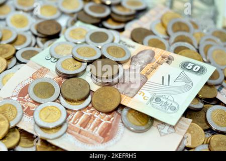 Pile di banconote e monete egiziane di 1 EGP LE una libbra egiziana e mezzo una libbra 50 cinquanta piasters, pile di sfondo di valuta egiziana, eco Foto Stock