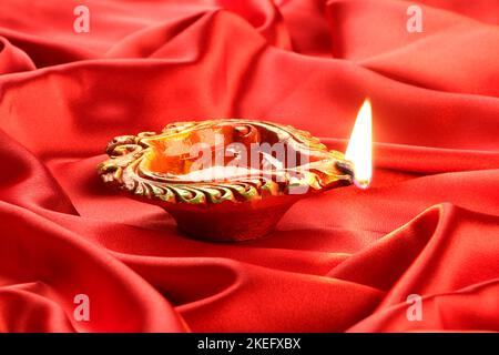 Fatti a mano di argilla Diwali lampada su raso rosso sfondo Foto Stock