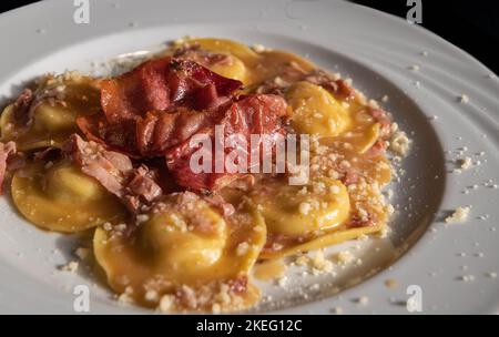 Agnolotti fatti a mano con speck, tipo di ravioli, tipica pasta all'uovo italiana piemontese, Italia settentrionale - fuoco selettivo con profondità bassa di Foto Stock