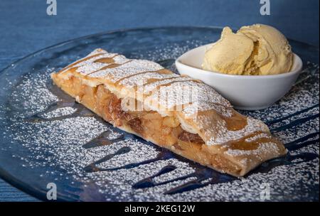 Strudel e gelato alla vaniglia sul piatto e zucchero a velo. Strudel di mele - Apfelstrudel - Strudel di mele Foto Stock