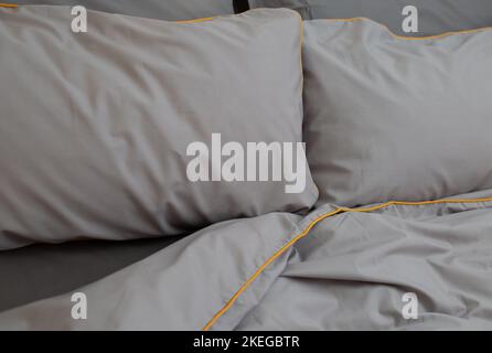 Letto grigio con lenzuola di cotone, coperta e due cuscini. Letto minimal, concetto di casa. Vista frontale Foto Stock