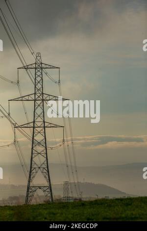 Piloni su una collina di Pennine all'alba vicino a Halifax, West Yorkshire, Regno Unito. I piloni, noti anche come torri di trasmissione dell’elettricità, sono i supporti strutturali che hanno portato la rete di linee elettriche aeree ad alta tensione del Regno Unito per quasi 100 anni. Oggi ci sono più di 90.000 piloni elettrici in tutta la Gran Bretagna, che coprono 4.300 miglia di rotta (7.000 chilometri). Foto Stock