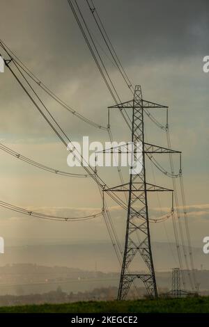 Piloni su una collina di Pennine all'alba vicino a Halifax, West Yorkshire, Regno Unito. I piloni, noti anche come torri di trasmissione dell’elettricità, sono i supporti strutturali che hanno portato la rete di linee elettriche aeree ad alta tensione del Regno Unito per quasi 100 anni. Oggi ci sono più di 90.000 piloni elettrici in tutta la Gran Bretagna, che coprono 4.300 miglia di rotta (7.000 chilometri). Foto Stock