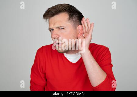 Poco felice di sentire l'uomo che mette mano sull'orecchio chiedendo a qualcuno di parlare in su Foto Stock