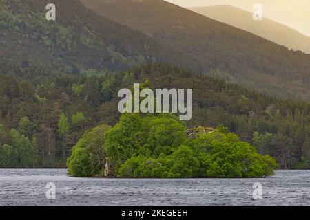 Vista sul mare della piccola isola con vegetazione lussureggiante nel mezzo dell'oceano vicino alle alte montagne con alberi alti e densi Foto Stock