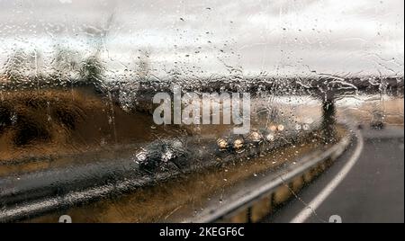 Vista attraverso il parabrezza del traffico in autostrada sotto la pioggia Foto Stock