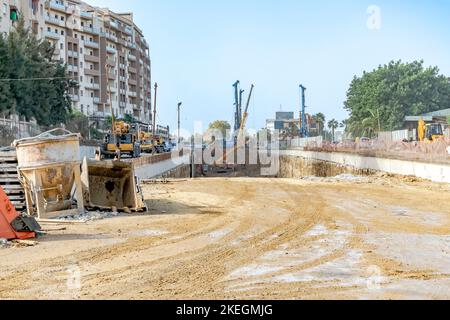 Cantiere di costruzione di tunnel nella RN 41 con macchinari da costruzione, camion, scavatori, gru e operai nel sottosuolo polveroso polveroso scavato su strada nazionale. Foto Stock