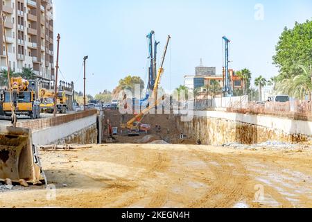 Cantiere di costruzione di tunnel nella RN 41 con macchinari da costruzione, camion, scavatori, gru e operai nel sottosuolo polveroso polveroso scavato su strada nazionale. Foto Stock