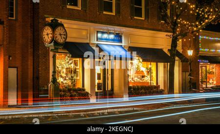 NEW CANAAN, CT, USA - 21 2021 DICEMBRE: Serata prima di Natale su Elm Street con Ralph Lauren storefront vicino orologio con luci e decorazioni natalizie Foto Stock