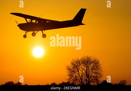 Cessna 152 atterrando al tramonto, Wellesbourne Airfield, Warwickshire, Regno Unito (G-BWNC) Foto Stock