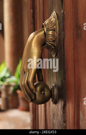 Bella Doorknoccker in ottone con forma a mano sulla vecchia porta in legno a Palma Spagna Foto Stock