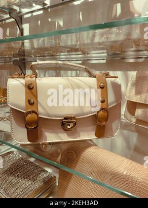 Piccola borsa donna di colore bianco e marrone alla moda sullo scaffale in vetro del negozio. Foto Stock