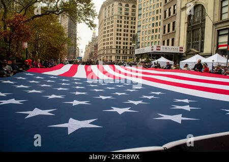 New York, Stati Uniti d'America. 12 Novembre 2022. I marinai statunitensi assegnati alla nave da trasporto anfibio di classe San Antonio, USS Arlington e i membri della II Marine Expeditionary Force si uniscono ai civili nel portare una gigantesca bandiera americana durante la New York City Veterans Day Parade, 11 novembre 2022 a New York City, New York. Credit: $MC3 Roan Smith/US Navy/Alamy Live News Foto Stock