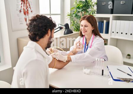 L'uomo e la donna che indossano l'uniforme del medico che hanno analisi del sangue in clinica Foto Stock