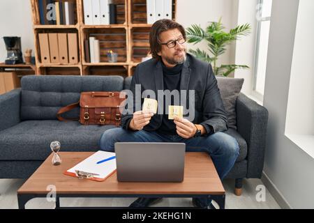 Bell'uomo di mezza età che lavora all'ufficio di consultazione sorridendo guardando al lato e fissando via il pensiero. Foto Stock