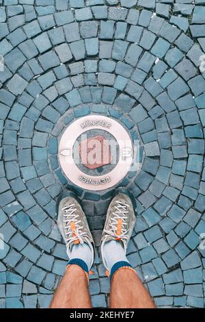 Un turista piedi sulle acciottolate vicino ad una pietra con l'iscrizione Munster in Germania Foto Stock