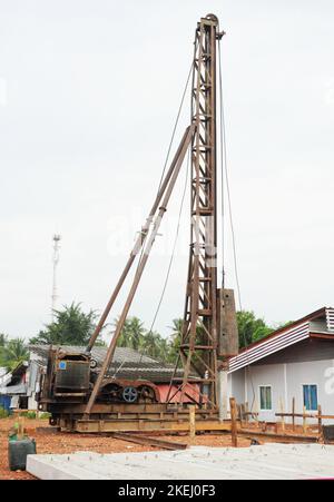 Il cumulo di calcestruzzo viene portato a terra in cantiere utilizzando una macchina palettatrice con cielo blu e nuvola bianca sullo sfondo, il martello diesel Foto Stock