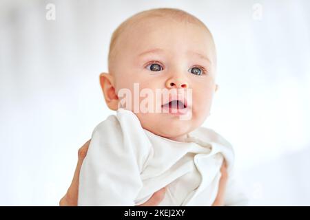 Il mondo sembra stupendo da qui: Un bambino tenuto da un genitore a casa. Foto Stock