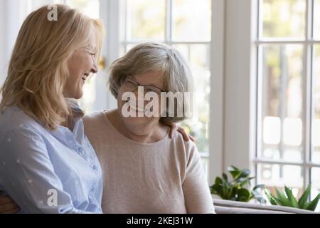Donna di mezza età che si prende cura della madre anziana dai capelli grigi Foto Stock
