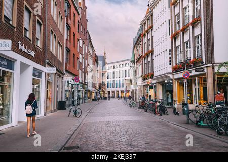 25 luglio 2022, Munster, Germania: Biciclette parcheggiate in una tranquilla strada cittadina tra vecchie case con squisita architettura gables nella città vecchia. Attractio di viaggio Foto Stock