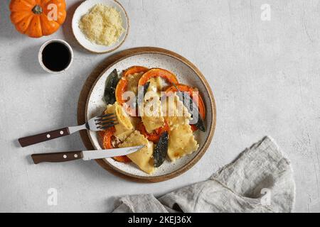 Ravioli di zucca fatti in casa con ricotta servito burro salvia , formaggio, pezzi di zucca e taglio di un ravioli. Vista dall'alto, spazio copia Foto Stock