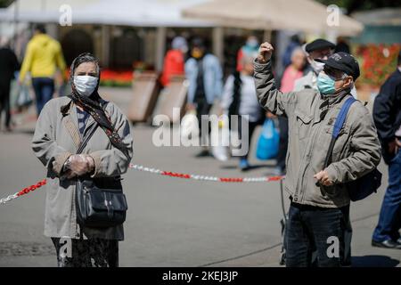 Bucarest, Romania - 16 aprile 2020: Gli anziani che indossano maschere protettive fanno il loro shopping in un mercato aperto occupato a Bucarest durante l'epidemia di covid-19 Foto Stock