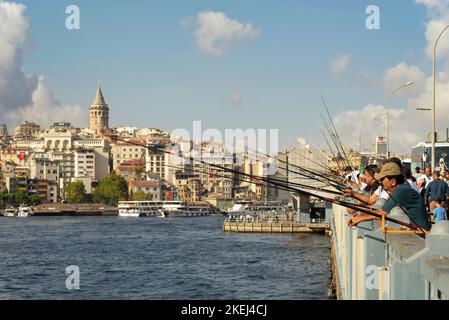 Istanbul, Turchia - 30 agosto 2022: Cittadini locali che pescano al Corno d'Oro sul Ponte di Galata prima del tramonto con lo skyline di Istanbul sullo sfondo, tra cui la Torre di Galata, nel quartiere di Eminonu Foto Stock