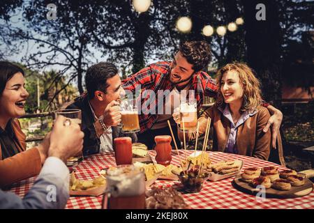 Gruppo di amici familiari a maglia stretta bere e mangiare insieme divertirsi in campagna nel fine settimana in una primavera crepuscolo - cibo, bevande, lifestyle con Foto Stock