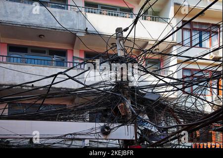 Mazzo di fili elettrici collegati ad un palo con edificio in background, Kathmandu, Nepal Foto Stock