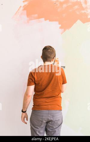 Giovane uomo con spatola e intonacatura di parete con stucco bianco fresco di finitura. Primo piano. Lavori di riparazione di casa. Foto Stock