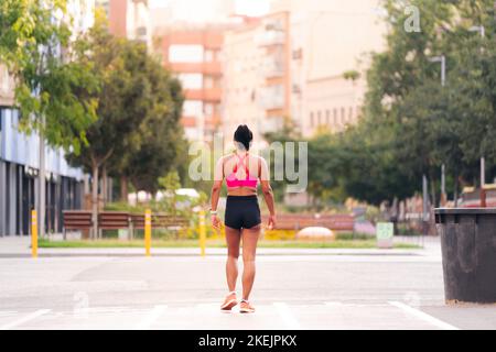 vista posteriore di un'atleta che cammina in città Foto Stock