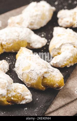 Biscotti arrotolati tradizionali ebraici Rugelach o Kifli Crescent ricoperti di zucchero a velo. Shortcrust appena sfornato Pasticceria croissant Confezione Foto Stock