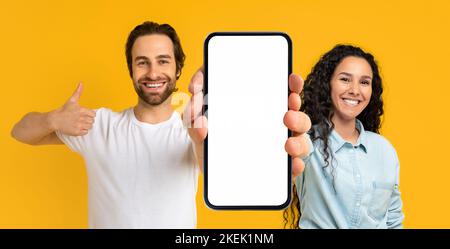 Felice uomo e donna europei millennial mostrare grande smartphone con schermo vuoto e pollice in su Foto Stock