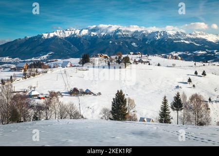 Splendido villaggio alpino e fantastico scenario invernale con montagne innevate sullo sfondo, villaggio di Pestera, Romania, Europa Foto Stock